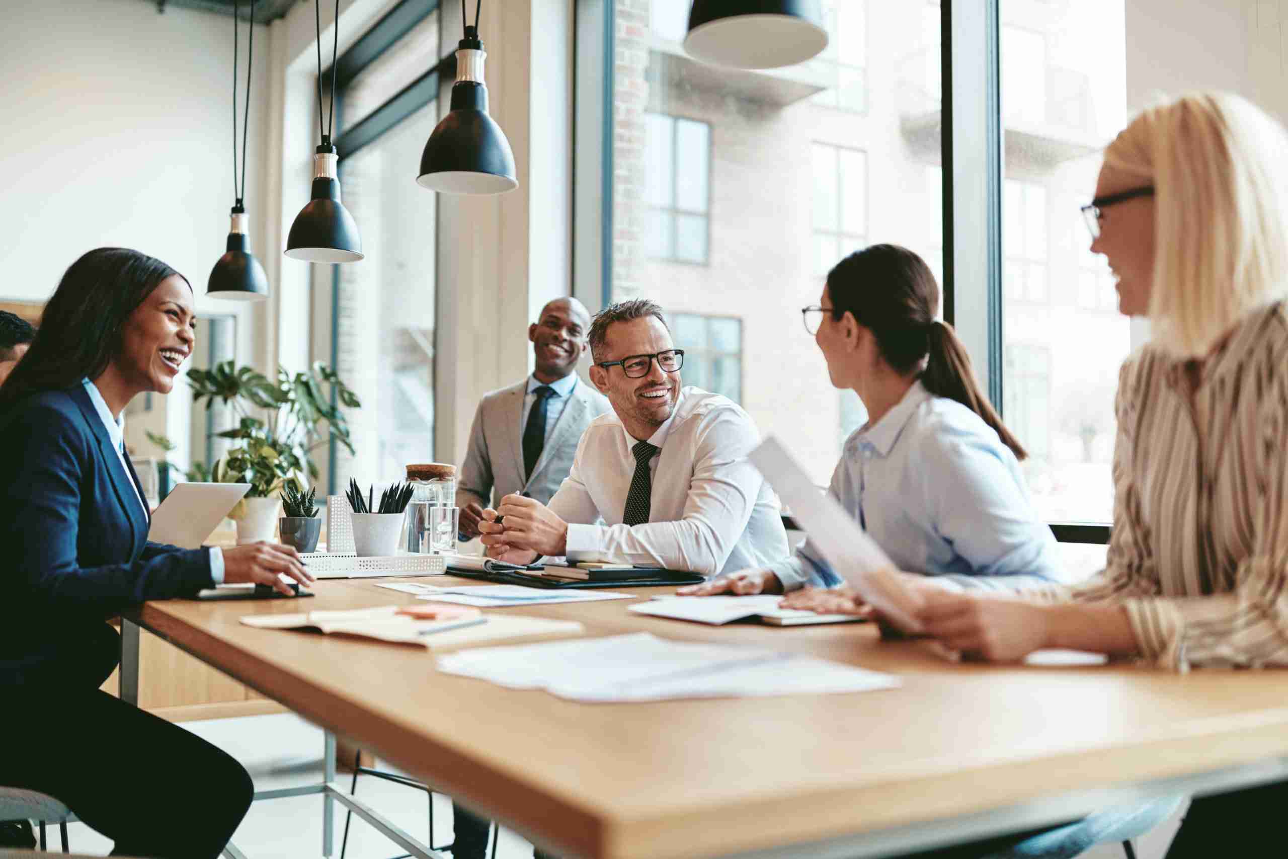 People smiling in meeting while lady keeps meeting minutes